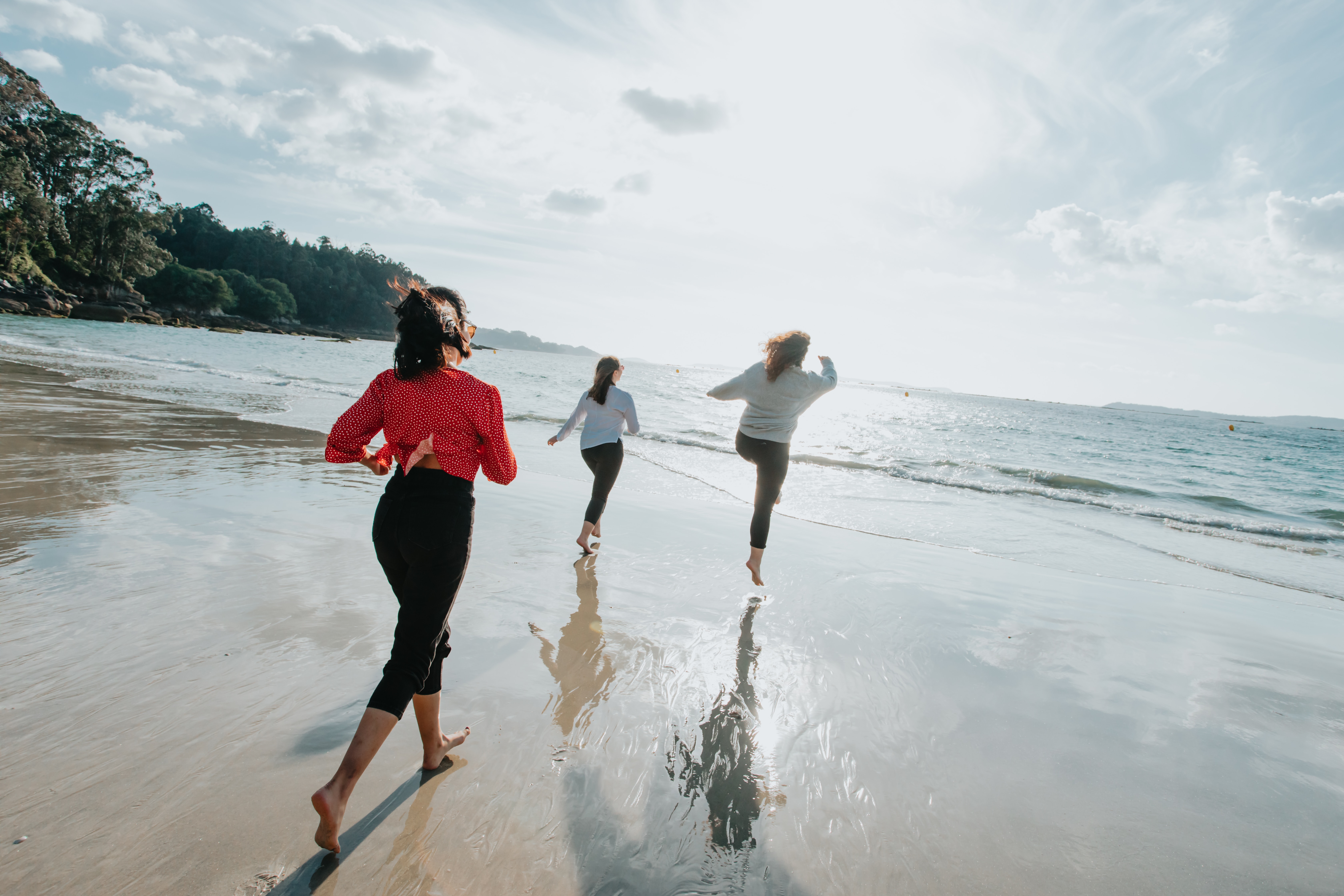 three women running into ocean